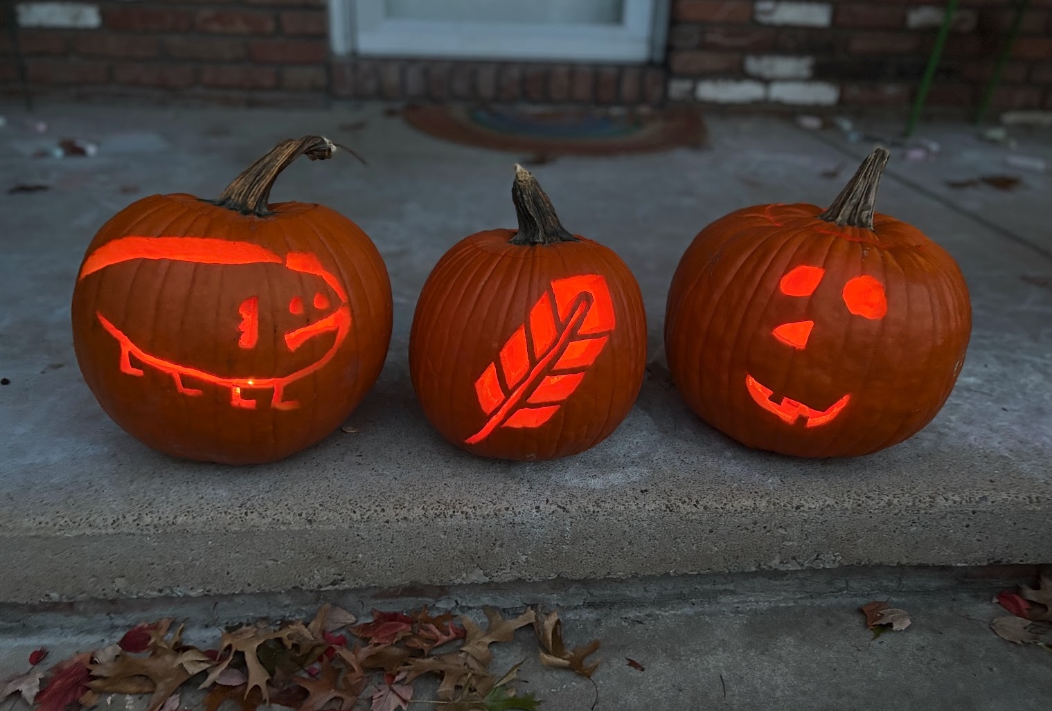 Three carved pumpkins, including one with the Quill Therapy Solutions logo.